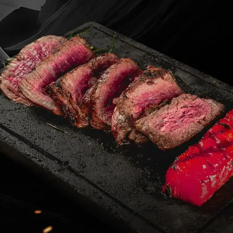 Una tabla de roca con trozos de un corte a la parrilla en Regio Norte, uno de los mejores lugares para cenar en Puebla con terraza.