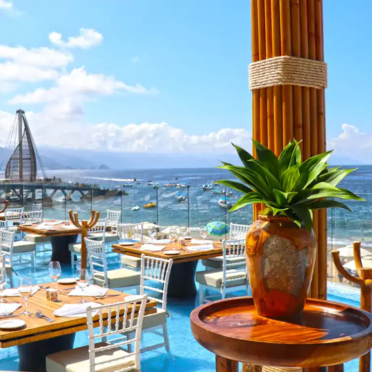 Vista panorámica hacia el océano desde las mesas a la orilla con la piscina de Mar Y Vino, una de las mejores opciones cerca de la playa en Puerto Vallarta.