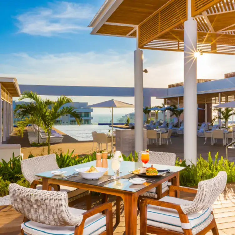 Mesas y pisos de madera y al fondo el mar en el Quinto at Vidanta Nuevo Vallarta, uno de los mejores restaurantes de cortes de la ciudad.