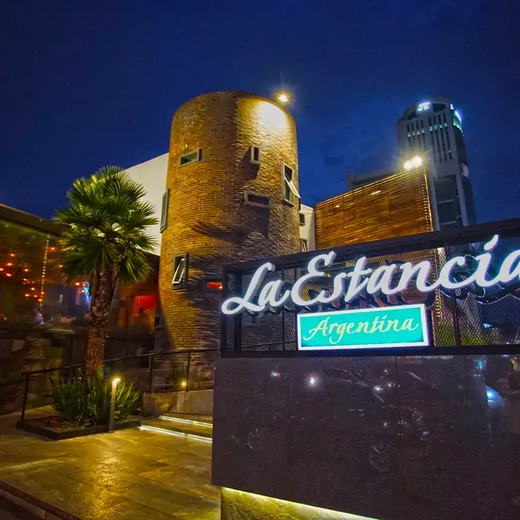 Fachada con una torre de ladrillo y una palmera en La Estancia Argentina - Juárez, uno de los mejores restaurantes argentinos con terraza en Puebla.