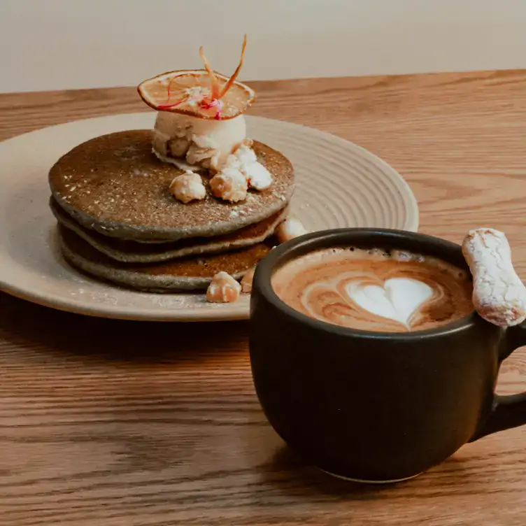 Tres pancakes de maíz azul y avena, decorados con helado y palomitas de maíz, acompañados de un café en El Americano Restaurante, uno de los mejores cafés para el desayuno en la CDMX.